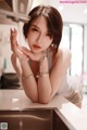 A woman sitting at a kitchen counter with her hand on her chin.