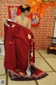 A woman in a red kimono sitting on the floor.