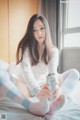 A woman sitting on a bed holding a can of soda.