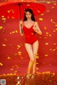 A woman in a red bathing suit holding an umbrella.