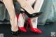 A pair of red and black high heels on a woman's legs.