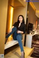 A woman sitting on top of a wooden shelf in a room.