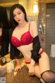 A woman in a red lingerie sitting on a counter.