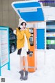 A woman standing in front of a vending machine in the snow.