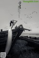 A woman sitting on top of a wooden boat surrounded by birds.