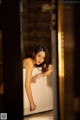 A woman leaning on a bathtub in a bathroom.