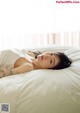 A woman laying on top of a white bed.