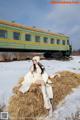 A woman sitting on a hay bale in front of a train.