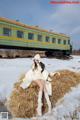 A woman sitting on a hay bale in front of a train.