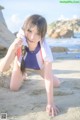 A woman in a bathing suit crouching on the beach.