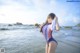 A woman in a bathing suit standing on the beach.