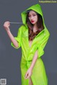 A woman in a green raincoat is posing for a picture.