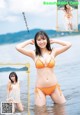 A woman in an orange bikini standing in the water.