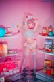 A woman in a bunny costume standing in front of a pink wall.