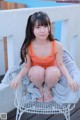 A little girl sitting on a white chair on a deck.