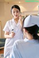 A woman in a white uniform talking to a nurse.