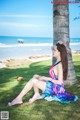 A woman sitting under a palm tree on the beach.