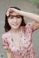 A woman in a pink floral dress posing for a picture.