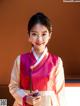 A woman in a pink and white hanbok holding a ball.