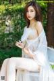 A woman in a white lingerie sitting on a white chair.