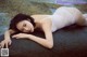 A woman in a white bodysuit laying on a rock.