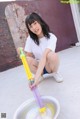 A woman kneeling down with a water gun in her hand.