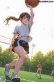 A girl in a white shirt and black shorts holding a basketball.