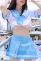 A woman in a blue and white sailor outfit posing by a pool.