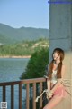 A woman tied up to a wall by the water.