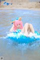 A woman in a pink wig is floating on an inflatable ring in the water.