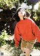 A young boy in a red sweatshirt and brown shorts blowing bubbles.