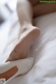 A close up of a woman's legs in white shoes on a bed.