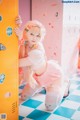 A woman in a pink and white outfit leaning against a yellow locker.