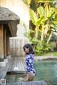 A woman in a blue and white bathing suit standing by a pool.