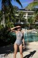 A woman in a bathing suit standing on a beach next to a pool.