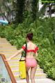 A woman in a red and white polka dot bikini with a yellow bag.