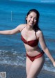 A woman in a red bikini standing on the beach.