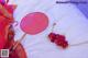 A red fan and a red flower on a white sheet.