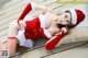 A woman in a santa claus outfit laying on a bed.