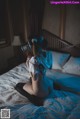 A woman sitting on a bed wearing a pair of headphones.