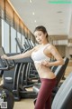 A woman in a white sports bra top and red leggings on a treadmill.