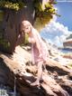 A woman in a pink dress standing on a log by the water.