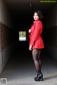 A woman in a red coat is standing in a tunnel.